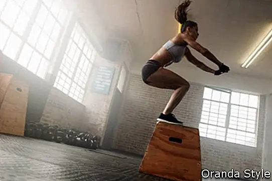 Image vue latérale de l'ajustement jeune femme faisant un exercice de saut de boîte