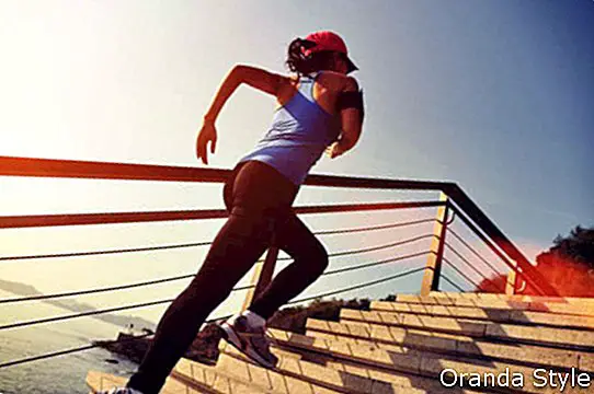gesunder Lebensstil trägt die Frau zur Schau, die oben auf Steintreppensonnenaufgangküste läuft
