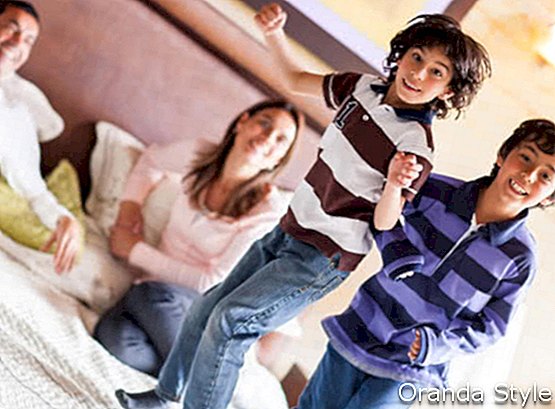 Boldog gyerekek ugrás a szülők ágyon, és szórakozás