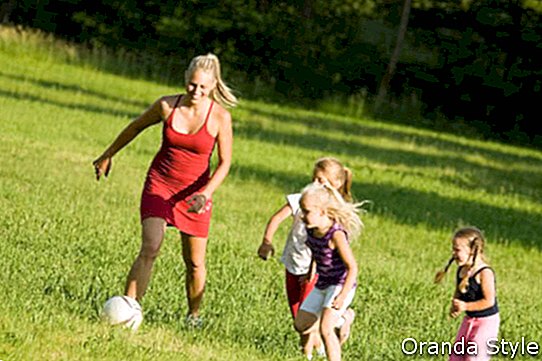 Mère avec deux filles jouant au football