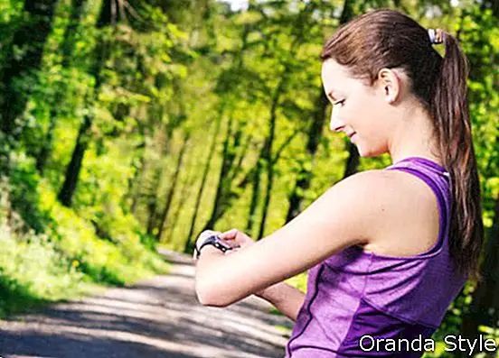 若い女性のジョギングをチェックしている彼女の時間の写真