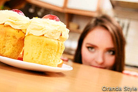 Bújva az asztal mögé nő bujkál, és nézett finom sütemény, tejszín és gyümölcs tetején