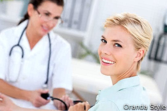 Orvos vesz vérnyomás mosolygó beteg orvosi rendelőben