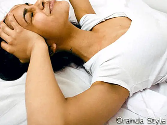 hübsche Brünette Frau im Bett Probleme mit Kopfschmerzen