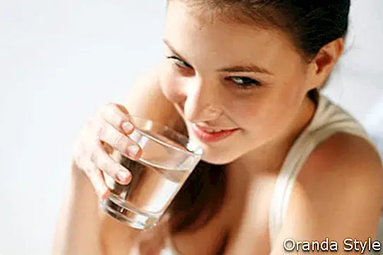 schöne Frau, die Glas Süßwasser isst