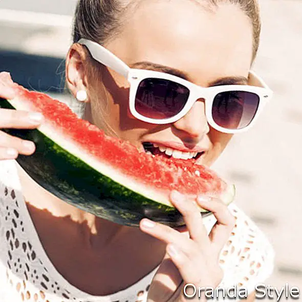 csokornyakkendő hajú, szőke lány napszemüveget viselő fehér nyári ruhában lédús görögdinnye harap
