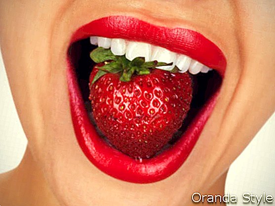 Frau mit den perfekten weißen Zähnen Erdbeere essend