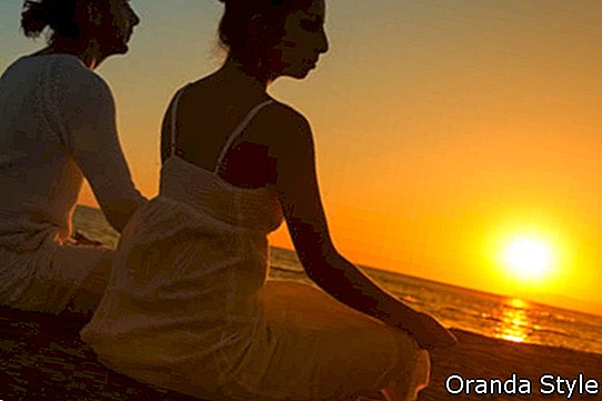 Paar macht Yoga-Übungen am Strand bei Sonnenaufgang