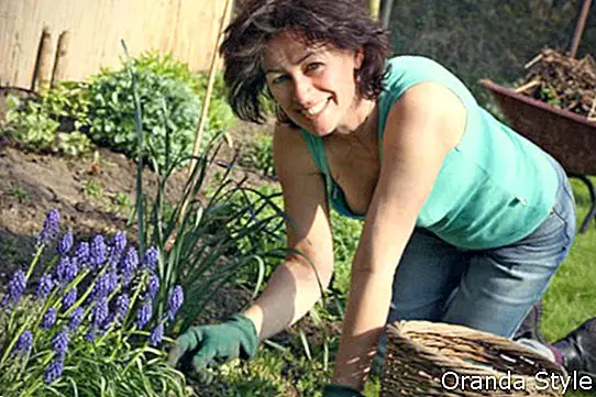 ein fälliger lächelnder weiblicher Gärtner, der im Garten arbeitet