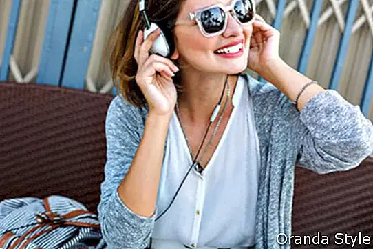 Молодий вродлива жінка, сидячи на пляжі, носити стильний повсякденний vintage стиль спорядження