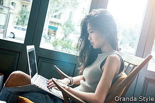 Gyönyörű fiatal ázsiai lány dolgozik egy laptop kávézóban