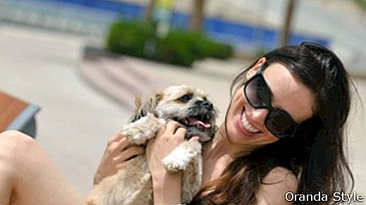 szép boldog fiatal nő fekete ruhában, aranyos kis kutya kölyökkutya szórakozni az utcán