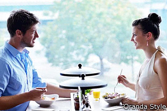 Egy fiatal pár ül az asztalnál, és ebédelni egy szabadtéri étteremben