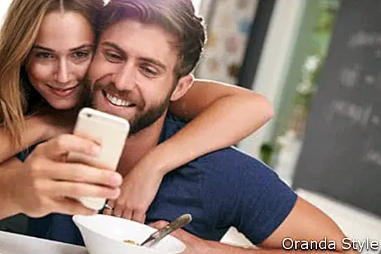 Paare, die Frühstück unter Verwendung Digital-Tablets und -telefons essen