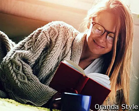 hübsches Mädchen Lesebuch mit Kaffee im Bett liegend