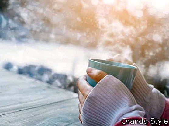 Oldalnézetből a nő kezében forró csésze kávét télen