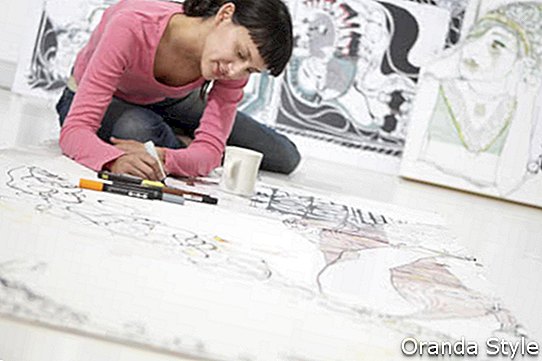Fiatal női művész támaszkodva nagy papír otthoni iroda