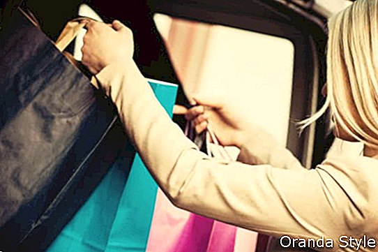 blonde Frau, die Einkaufstaschen in Auto einsetzt