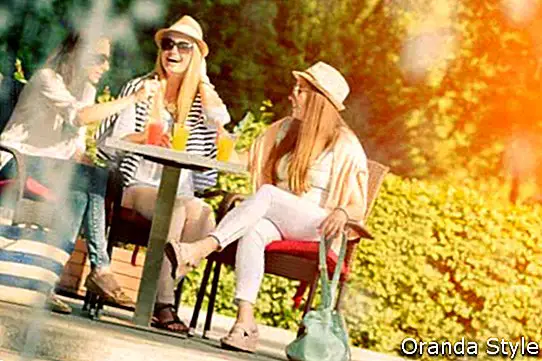 Drei attraktive Freundinnen, die Cocktails in einem Café im Freien genießen