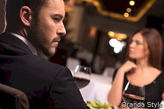 Durchdachte junge Paare, die im Restaurant sitzen und weg schauen
