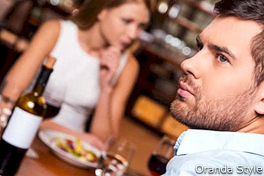 Frustrierter junger Mann, der beim Sitzen zusammen mit seiner Freundin in Restaurant 2 weg schaut