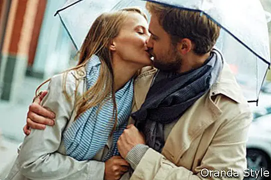 Влюбена млада влюбена двойка под чадър под дъжда