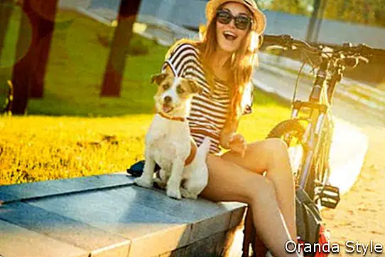 Boldog csípő lány kutyájával és kerékpáros a városban