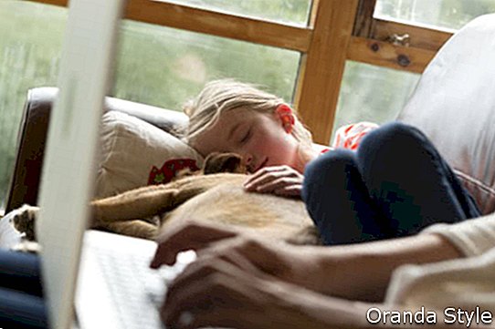 Nő használ egy laptop lányával és háziállat kutya együtt alszik mellette
