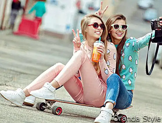 Hippie-Freundinnen, die in Mode ein Selbstfoto auf den Straßensitzplätzen auf Skateboard machen, kleiden den Moment mit moderner Digitalkamera ewig