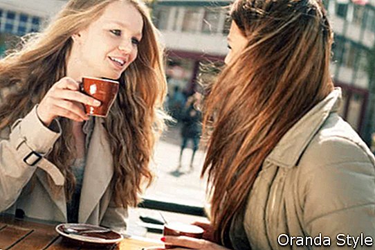 Zwei junge Freundinnen, die Kaffee im Café sprechen und trinken