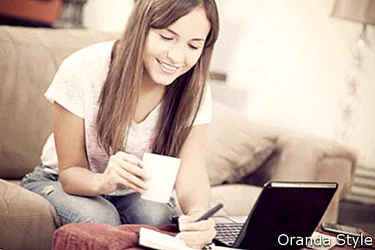 Frau zu Hause mit Laptop und Tasse Kaffee