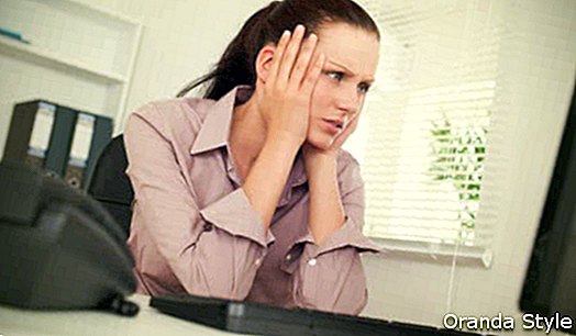 Gebohrte unglückliche junge Geschäftsfrau am Schreibtisch im Büro