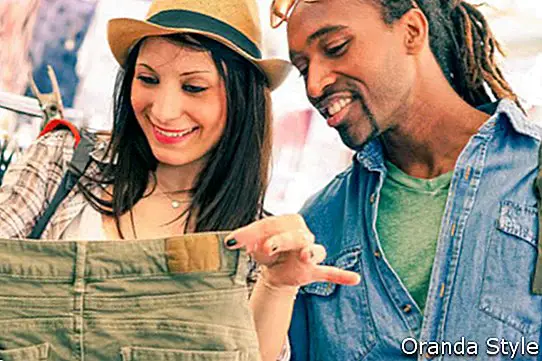 Zwischen verschiedenen Rassen junge Paare, die Kleidung am Straßenshopmarkt suchen