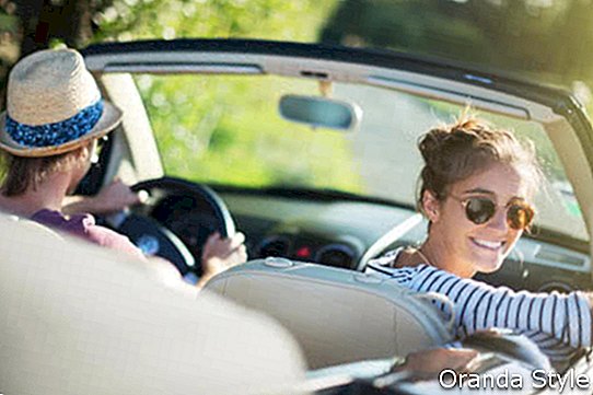 Jauns, moderns pāris, laimīgs, vadot savu kabrioletu automašīnu pa lauku ceļu vasarā