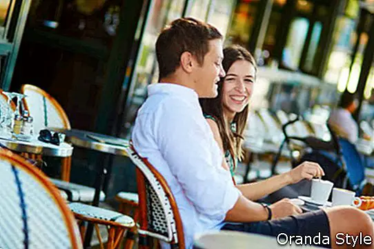 Trinkender Kaffee der jungen romantischen Paare und Essen von traditionellen französischen Hörnchen in einem gemütlichen Café im Freien in Paris