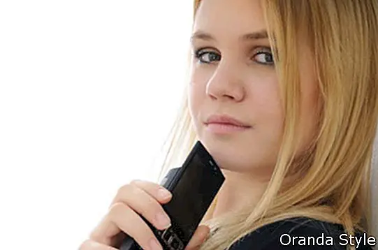 Плавокоса замишљена млада жена држи мобител