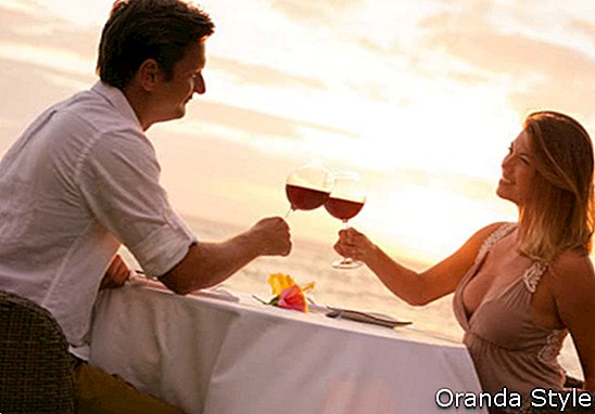 Paare, die romantisches Sonnenuntergangabendessen auf dem Strand teilen
