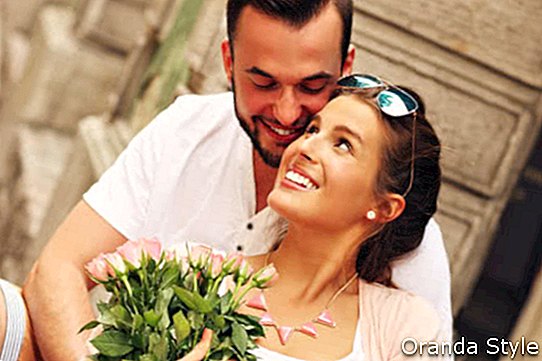 Снимка на млада романтична двойка с цветя в града