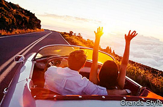 Romantyczna młoda para korzystających z zachodu słońca w klasycznym samochodzie sportowym w stylu vintage