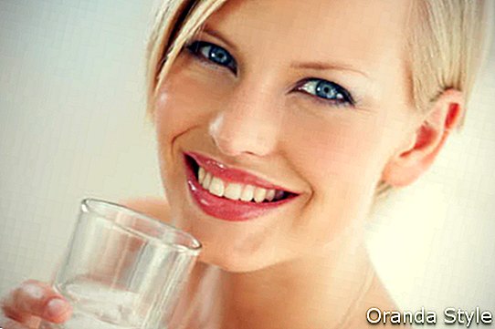blonde Frau mit kurzem Haarschnitt ein Glas Wasser trinkend