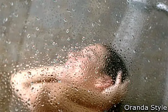 Unfocused Portrait einer Frau, die durch den Badbildschirm mit kleinen Tropfen duscht