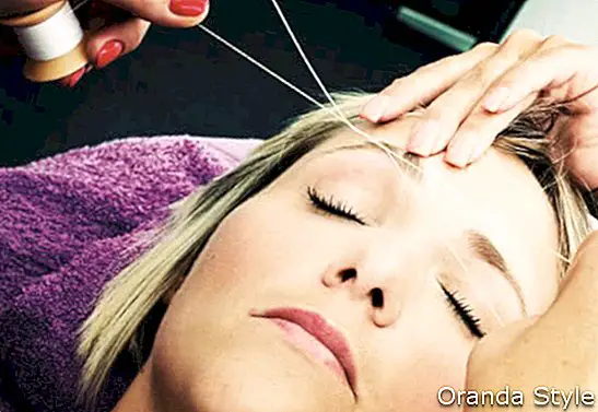 Kosmetikerin macht Haarentfernung Threading-Verfahren, blonde Frau im Salon