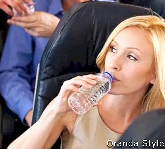 blond kvinde drikker vand på flyet