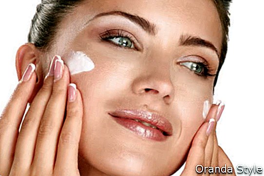 hermosa modelo aplicando crema cosmética en su rostro