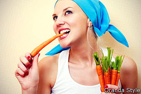 Moteris baltais marškiniais valgo morkas
