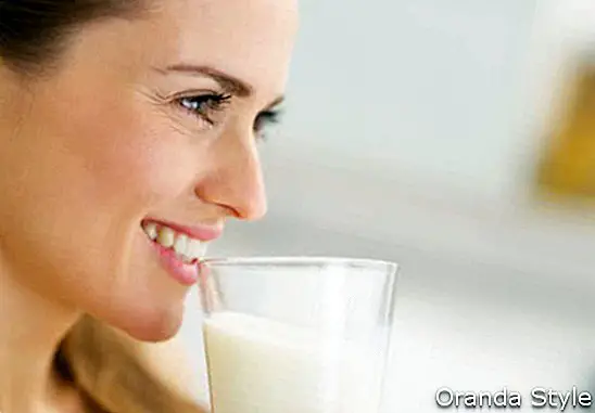 Laimīga jauna mājsaimniece dzer pienu