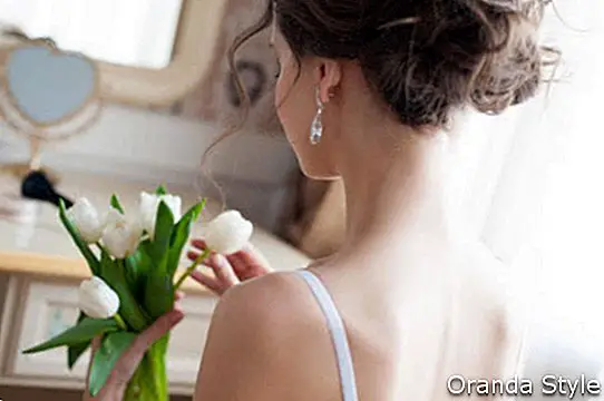 joven bella mujer con ramo de tulipanes blancos delante del espejo