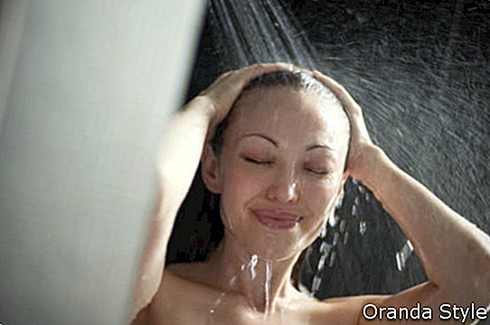 Атрактивна смесена жена, вземаща душ с ръце в косата