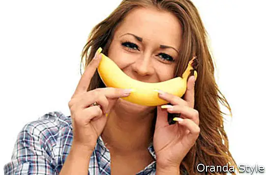 момиче, изолирани на бял фон, държи банан до устата