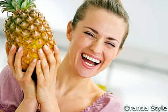 Щастлива млада домакиня, която държи свеж ананас